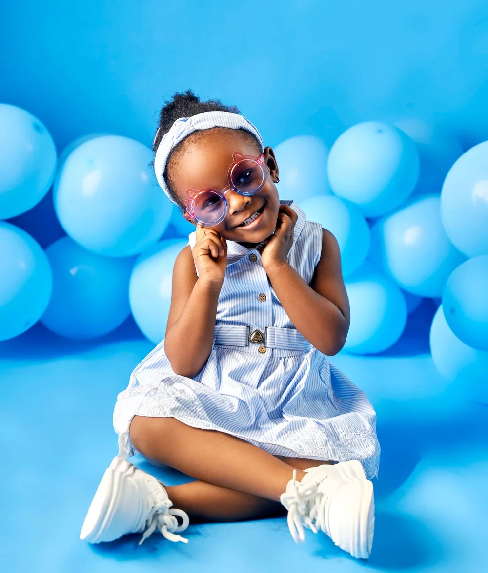 Smiling girl in a blue striped dress and pink glasses