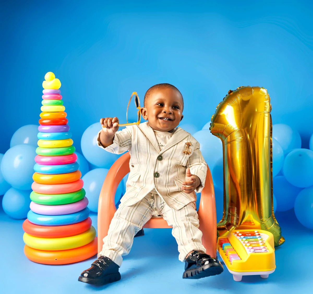 Smiling baby in a cream suit with colourful toys